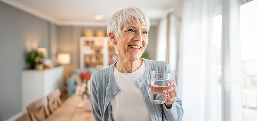 A smiling woman holding a glass of water.